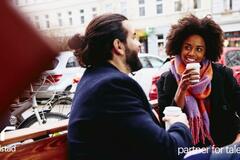 dos personas platicando, tomándose un café.