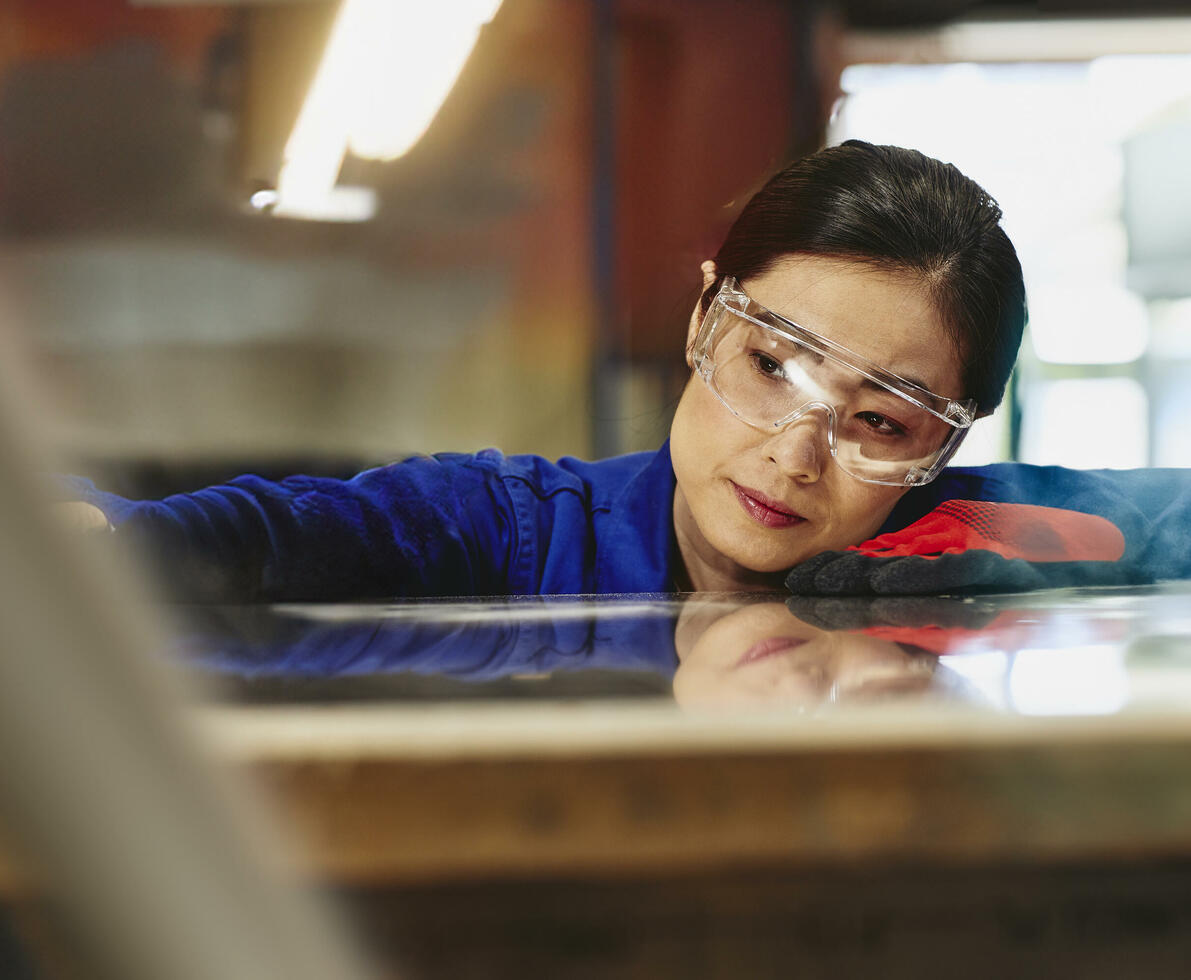 Womale wearing safety glasses and gloves watching a process closely.
